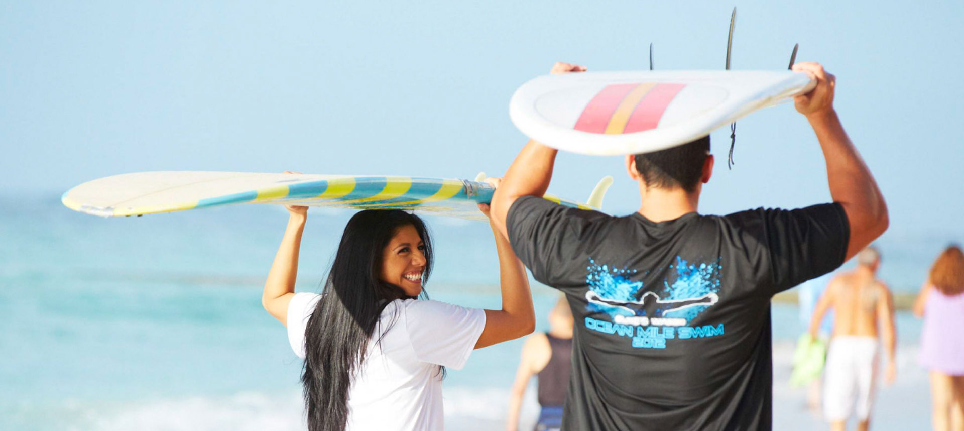 Friends carrying surfboards above their heads